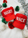 Al + Gray Graphic Tees Naughty or Nice puff hats with bold text, featuring playful holiday-themed designs in black and red.