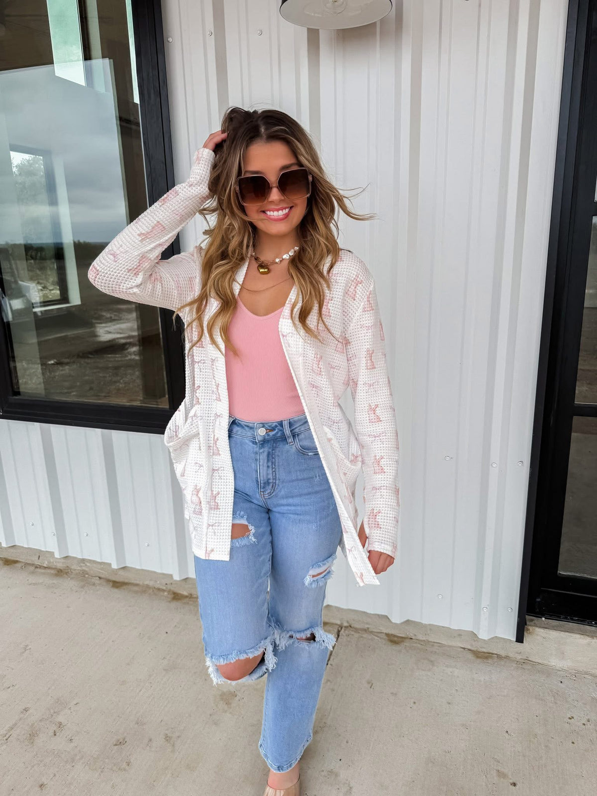 Pink Spring Lola Cardigan by BLAKELEY, lightweight knit with long sleeves and button closure, styled on a hanger.
