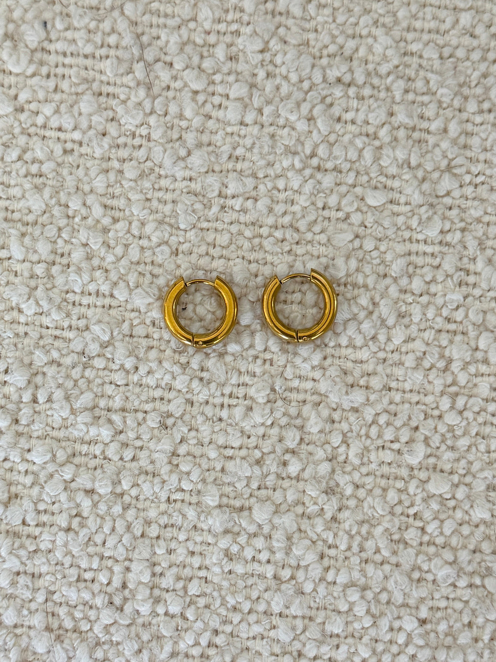 Gold Huggies earrings by Chansuttpearls featuring small, shiny gold hoops with a smooth finish.