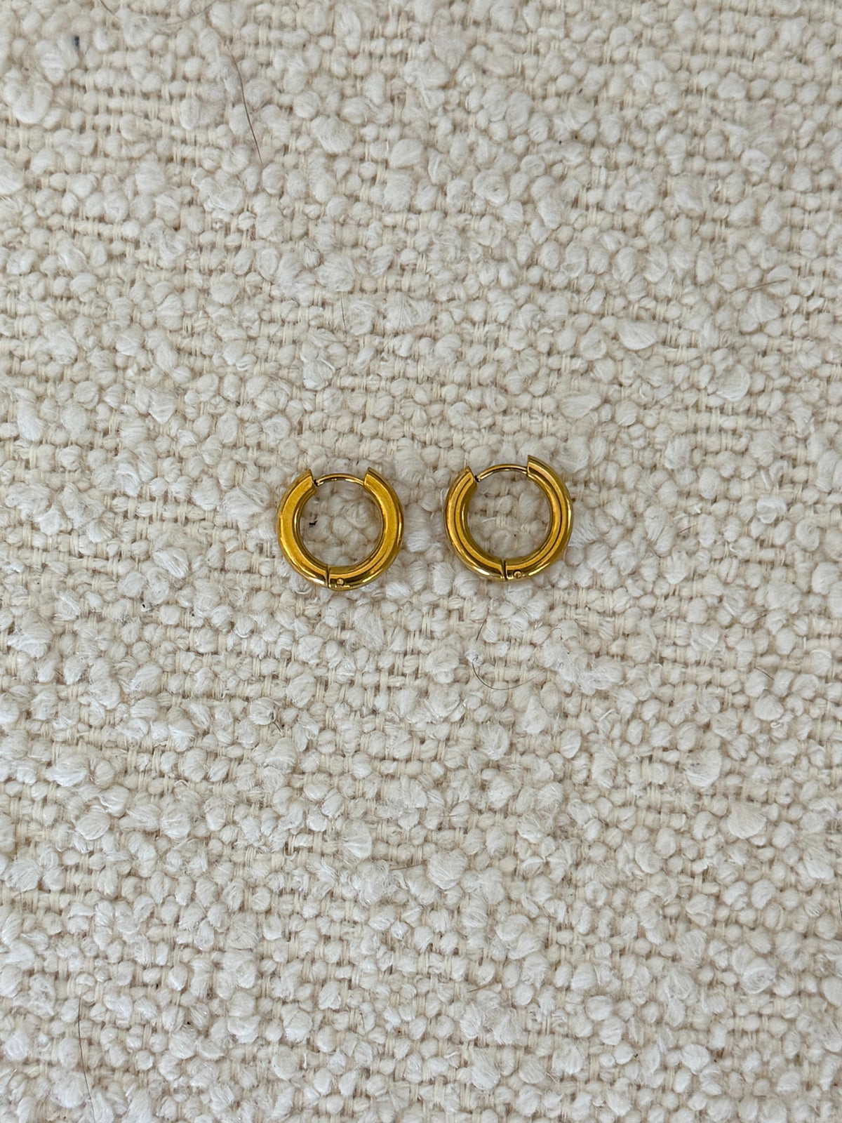 Gold Huggies earrings by Chansuttpearls featuring small, shiny gold hoops with a smooth finish.