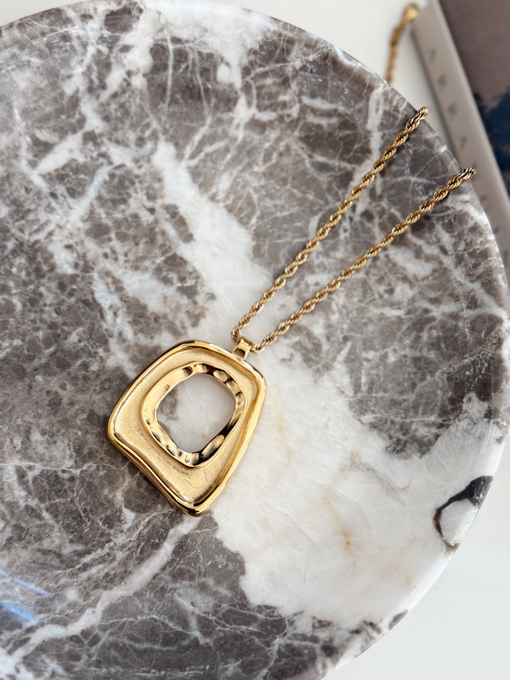 Gold Taylor necklace by Chansuttpearls featuring a delicate chain and elegant pendant on a neutral background.