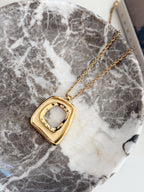 Gold Taylor necklace by Chansuttpearls featuring a delicate chain and elegant pendant on a neutral background.