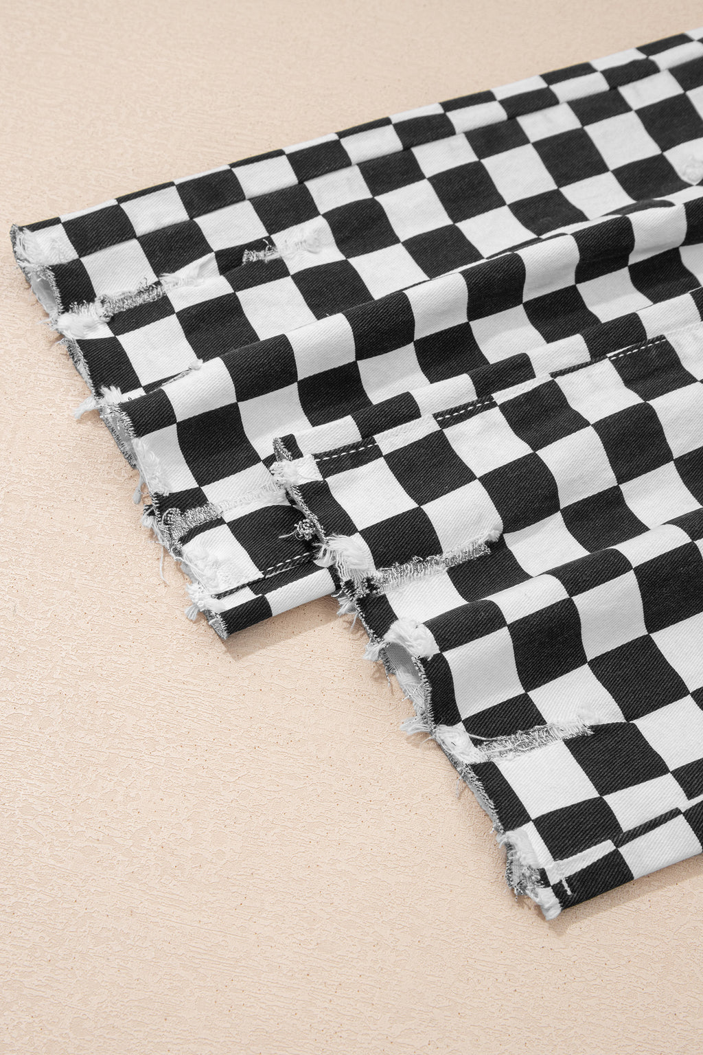 Black checkerboard print distressed raw edge cropped jeans by Dear-Lover Dropshipping, showing the distressed holes and raw hem detail.