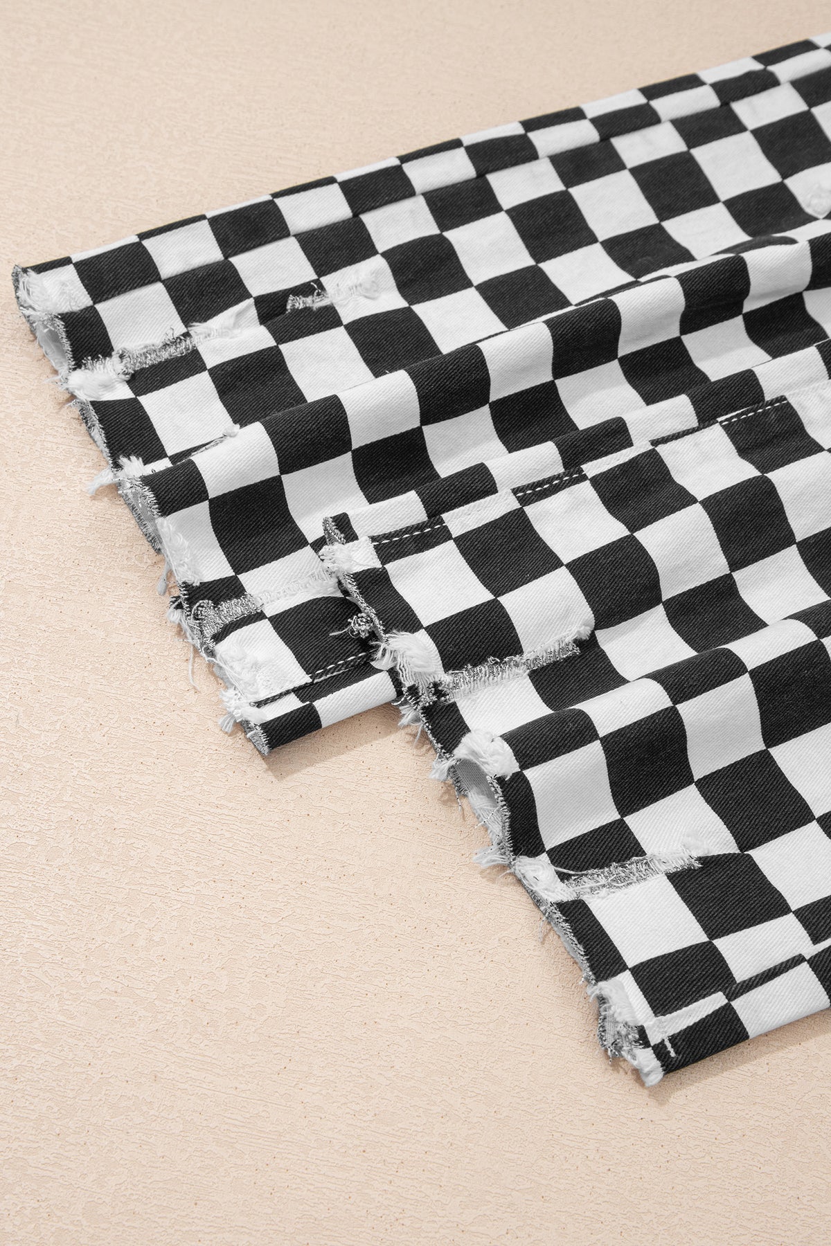 Black checkerboard print distressed raw edge cropped jeans by Dear-Lover Dropshipping, showing the distressed holes and raw hem detail.