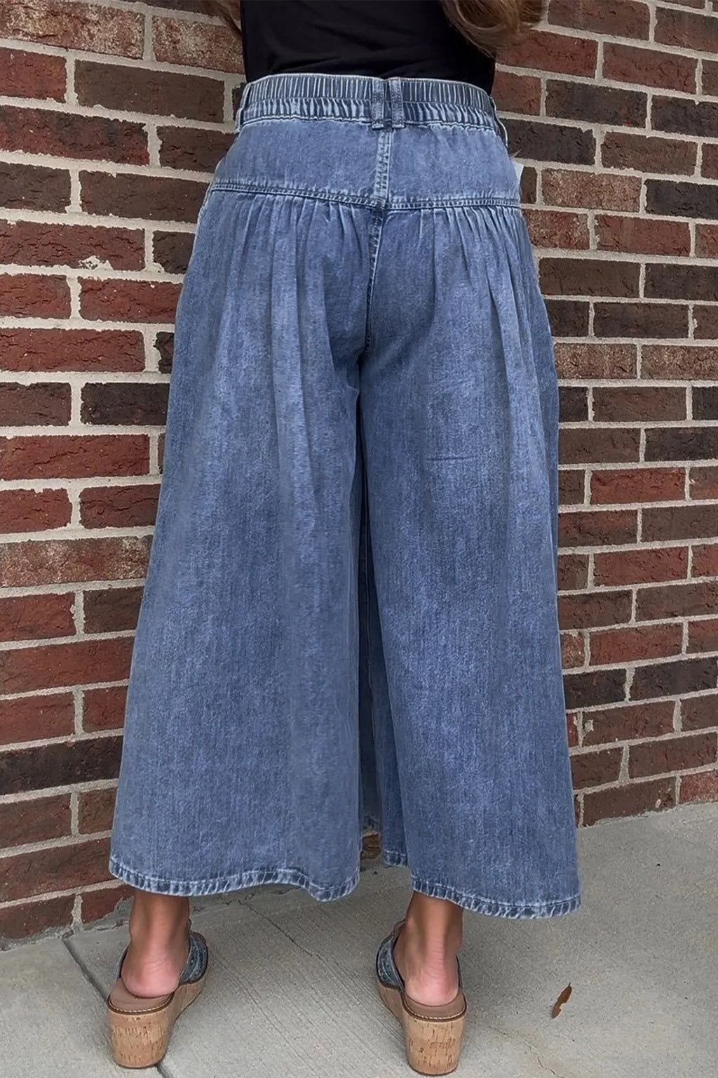 Dusk blue high-rise wide-leg denim pants with buttons and pleats, cropped length, made of cotton-polyester blend.