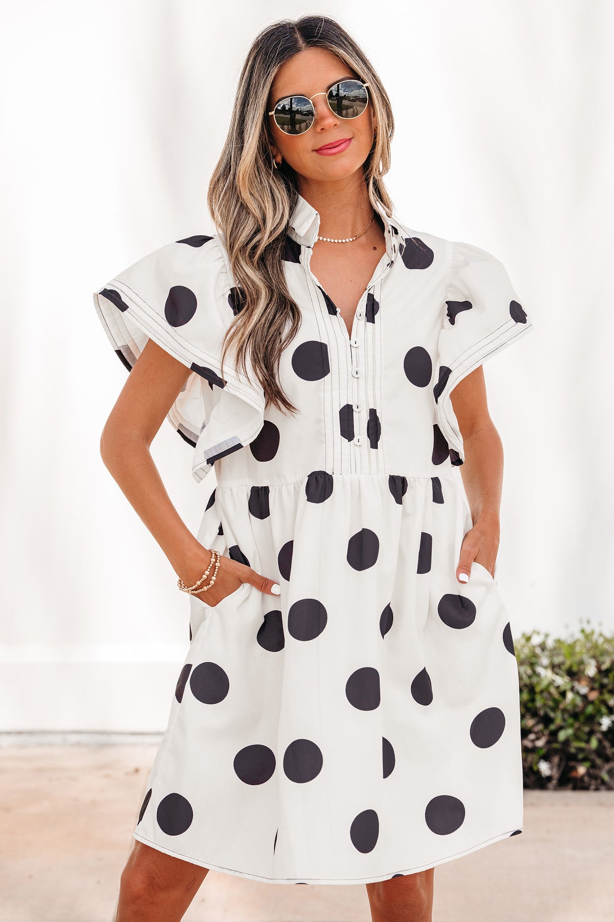 White polka dot print mini dress by Dear-Lover with ruffled short sleeves, half-button front, and loose fit in polyester fabric.