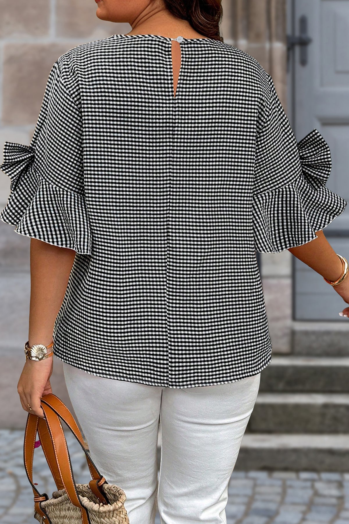 Black plus size plaid jumper with bow detail, bell sleeves, and round neck, made of polyester and elastane for a comfortable fit.