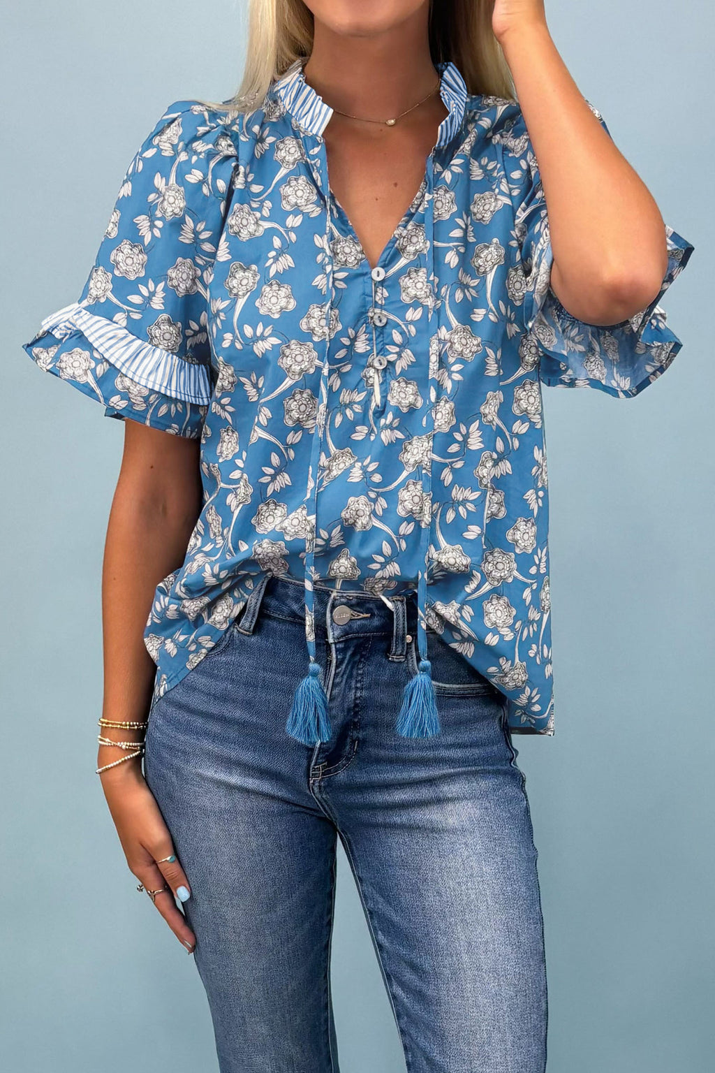 Blue floral print blouse by Dear-Lover with striped details, short sleeves, button tie neck, made of 100% cotton.