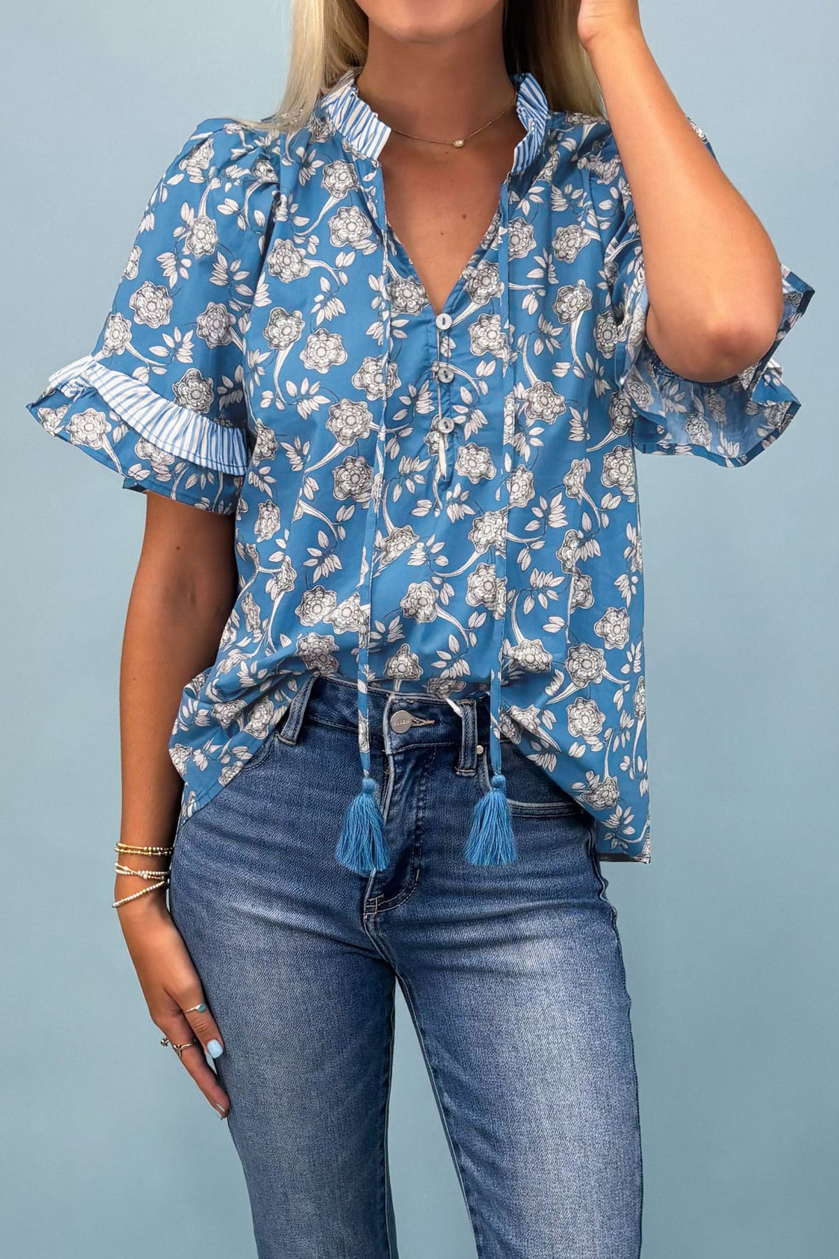 Blue floral print blouse by Dear-Lover with striped details, short sleeves, button tie neck, made of 100% cotton.