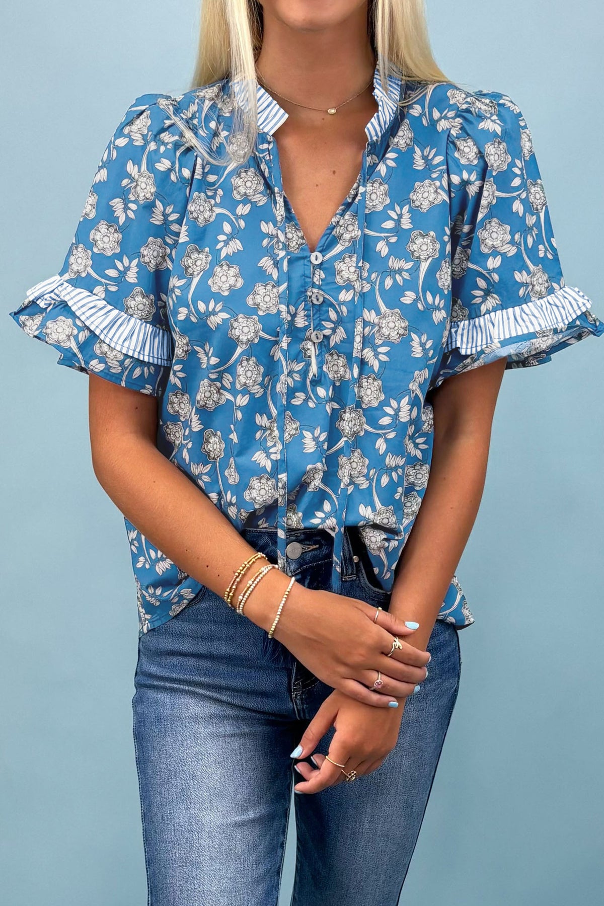 Blue floral print blouse by Dear-Lover with striped details, short sleeves, button tie neck, and made of 100% cotton.