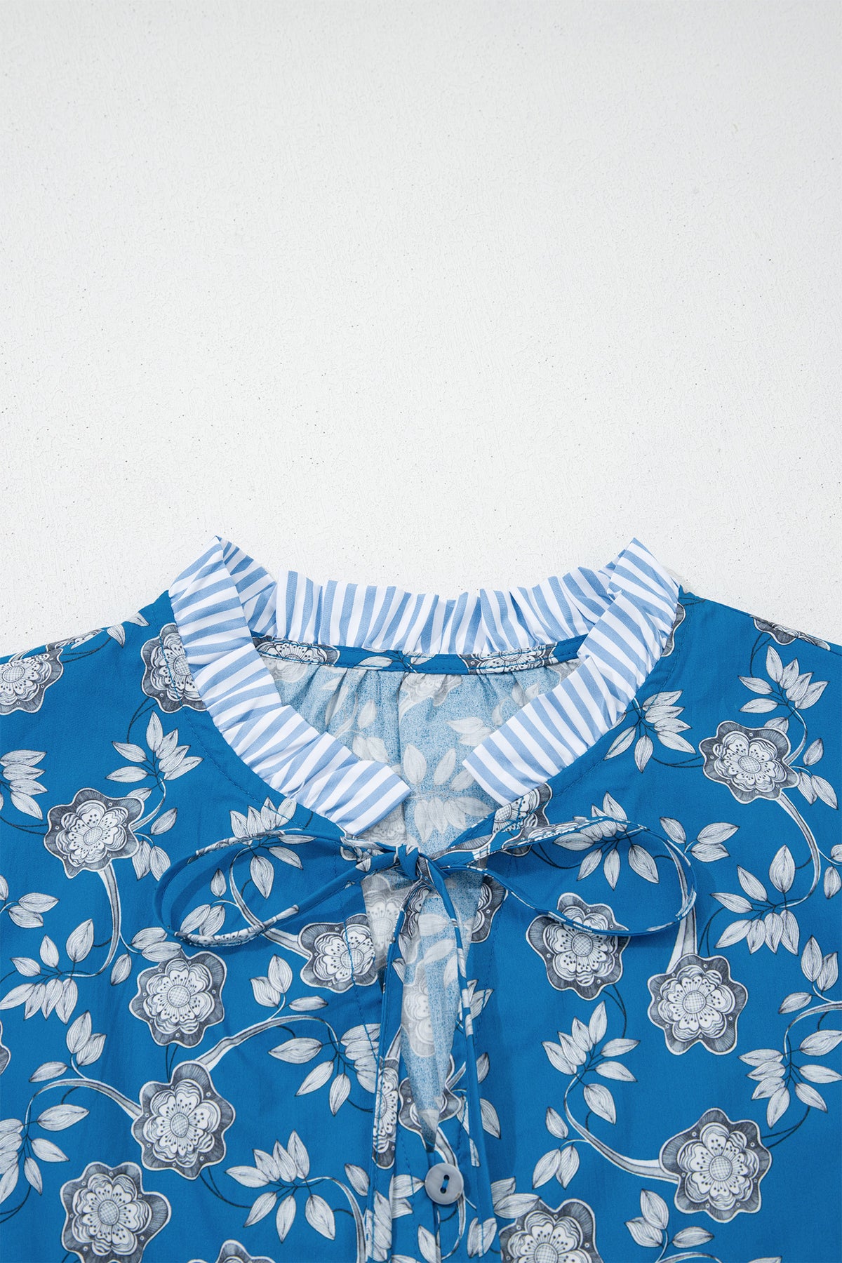 Blue floral print blouse by Dear-Lover with button tie neck, striped details, short sleeves, made of 100% cotton.