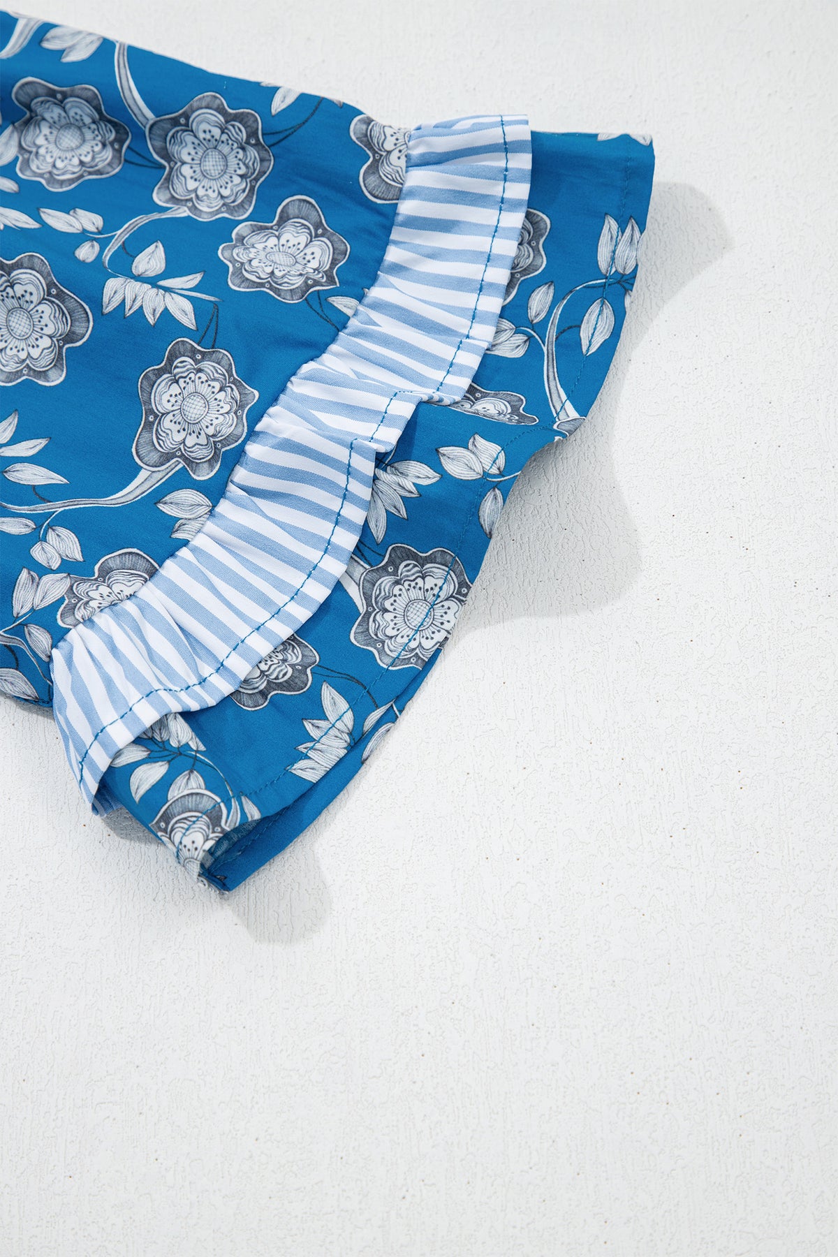 Blue floral print blouse by Dear-Lover with striped details, button tie neck, and short sleeves, made of 100% cotton.