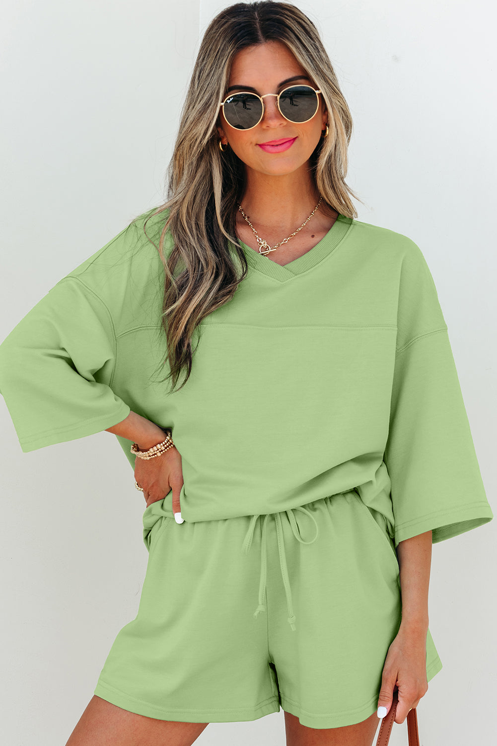 Meadow Mist Green solid two-piece set with loose V-neck half-sleeve tee and shorts, made of polyester, cotton, and elastane.