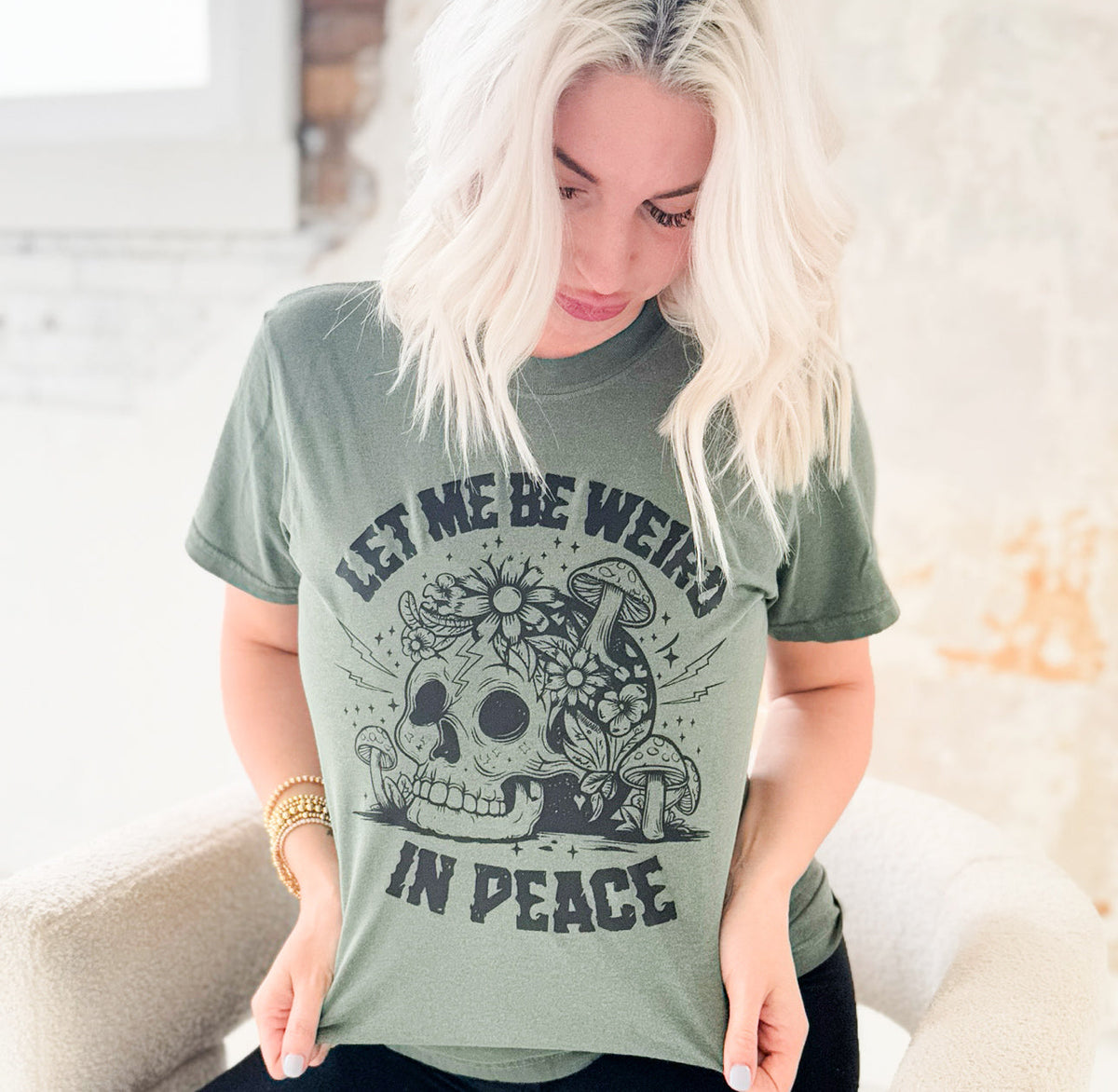 Women’s moss green graphic T-shirt by Envy Stylz Wholesale featuring "Let Me Be Weird In Peace" design.