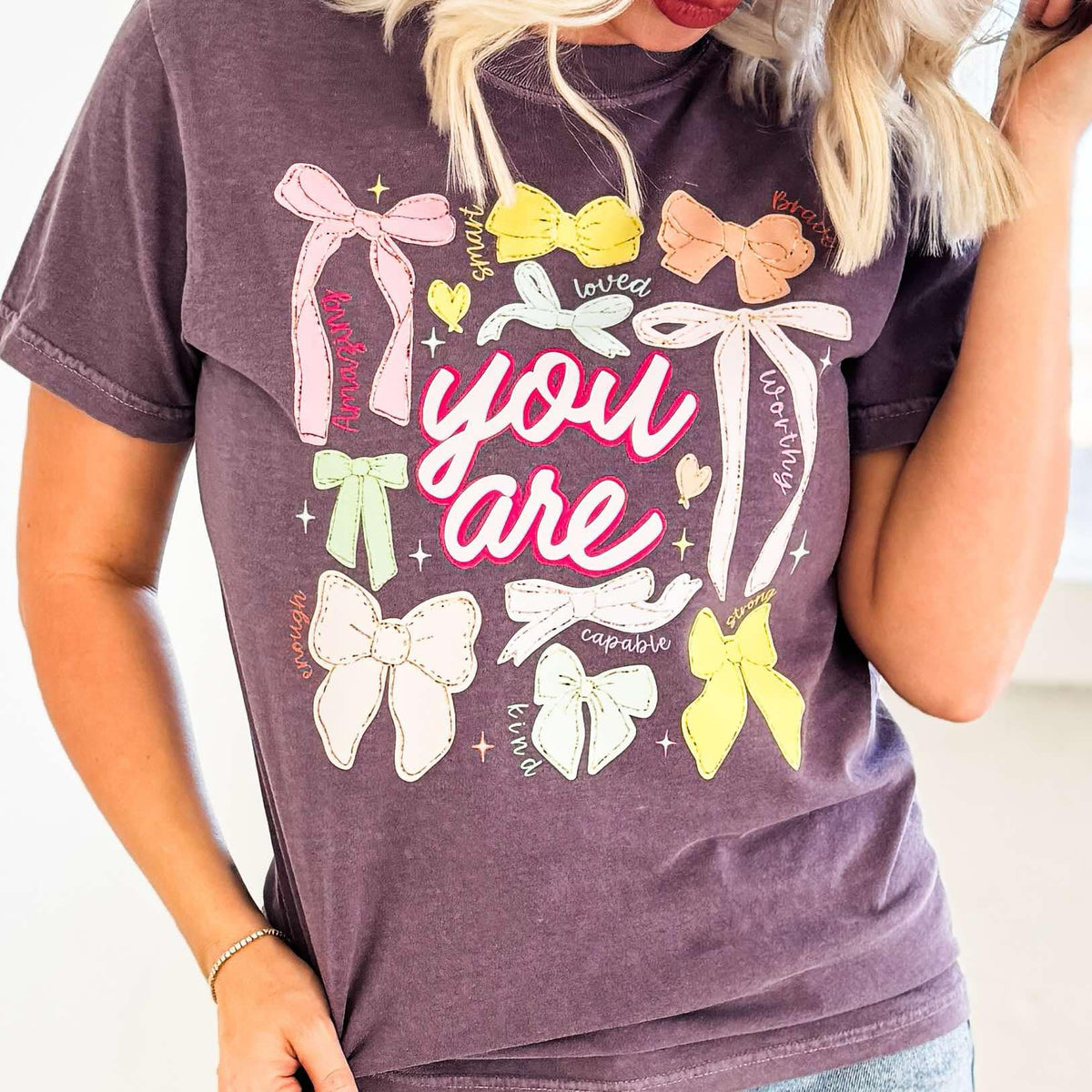 Women’s You Are Colorful Bows graphic T-shirt by Envy Stylz Wholesale, featuring vibrant bow designs on a comfortable tee.