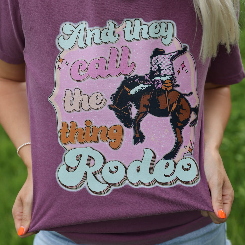 Women’s Call The Thing Rodeo graphic T-shirt by FestiviTees, featuring colorful rodeo-themed print on berry-colored shirt.