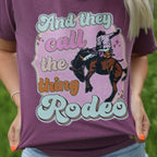 Women’s Call The Thing Rodeo graphic T-shirt by FestiviTees, featuring colorful rodeo-themed print on berry-colored shirt.