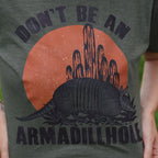 Women’s graphic T-shirt by FestiviTees featuring a playful "Don't Be An Armadillhole" design on a casual shirt.