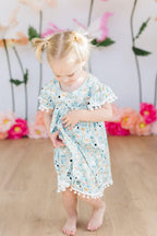 Cute baby girl wearing a pink Mila & Rose Furry Friends Pom Pom Dress with fluffy pom poms for ages 12-24 months.