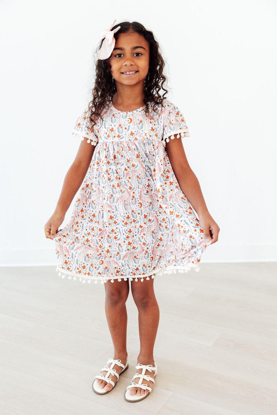Mila & Rose® Unicorn Soiree Pom Pom Dress for toddlers, pink and white dress with colorful pom poms and festive design.