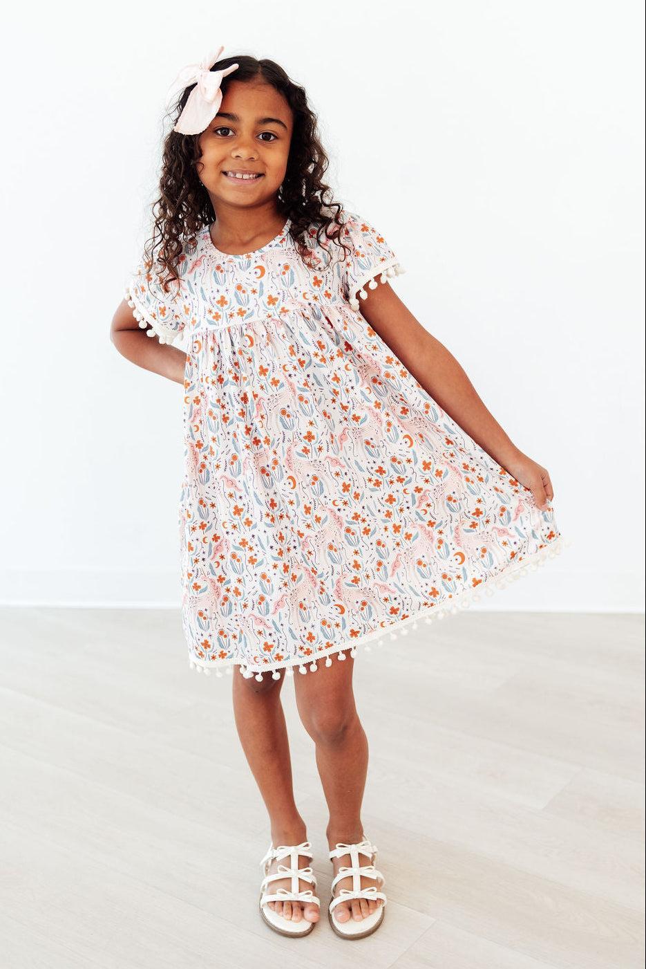 Mila & Rose® Unicorn Soiree Pom Pom Dress for toddlers, pink and white dress with colorful pom poms, suitable for special occasions.
