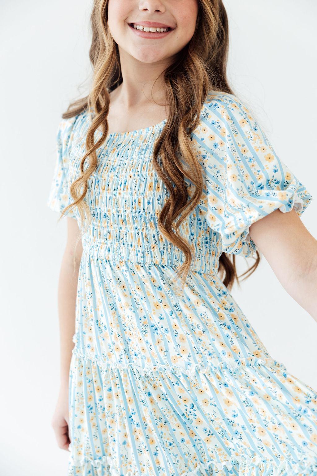 Mila & Rose smocked ruffle dress for toddlers, featuring buttercup blooms pattern with ruffled shoulders and smocked bodice.