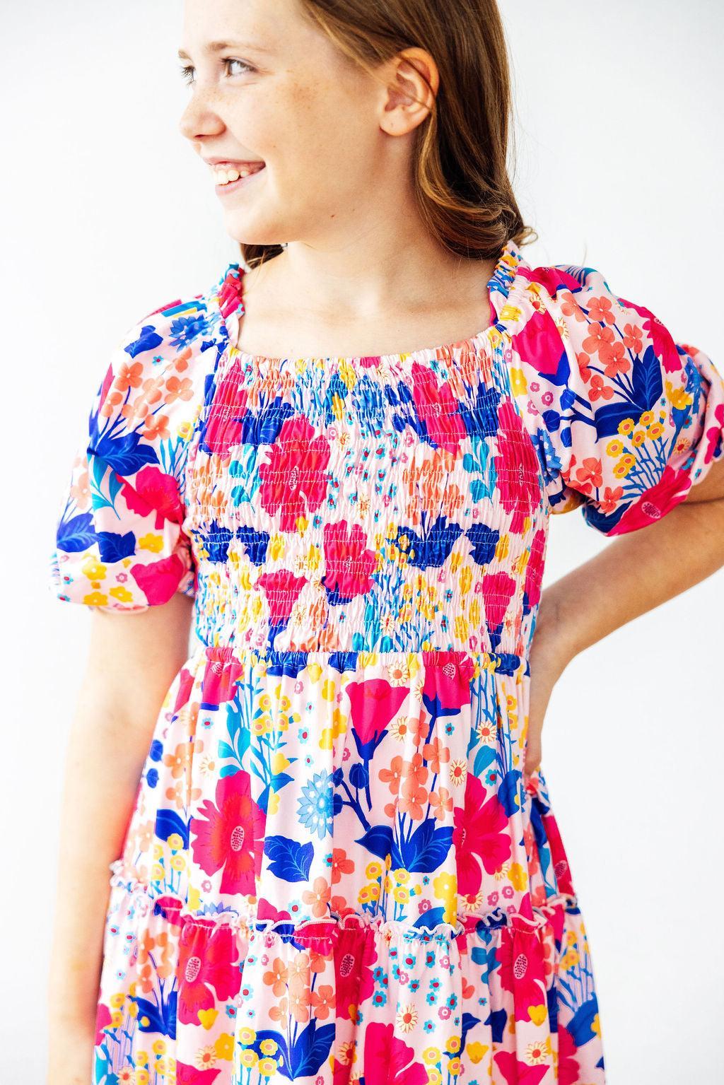 Mila & Rose Sunshine Garden smocked ruffle dress for toddlers, featuring floral print, ruffled sleeves, and smocked bodice.