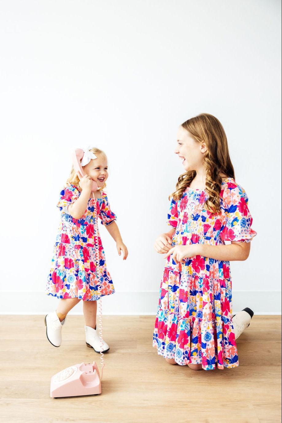 Mila & Rose sunshine garden smocked ruffle dress for toddler girl, featuring colorful floral pattern and ruffled neckline.