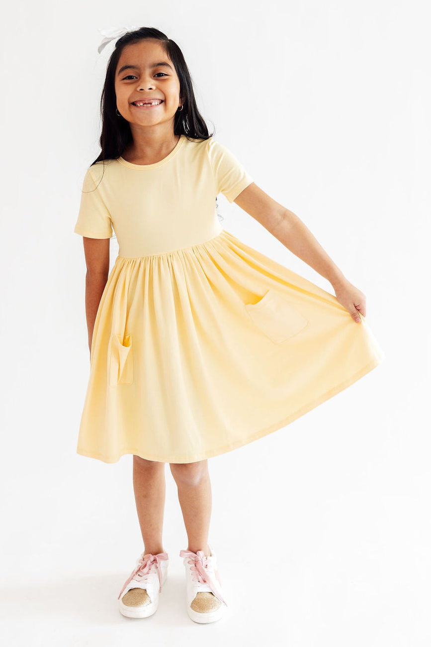 Butter yellow Mila & Rose S/S pocket twirl dress for babies, featuring a playful, twirling design and comfortable short sleeves.
