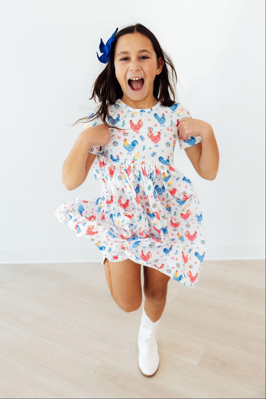 Mila & Rose rainbow rooster print S/S pocket twirl dress for girls, featuring colorful pattern and comfortable design.