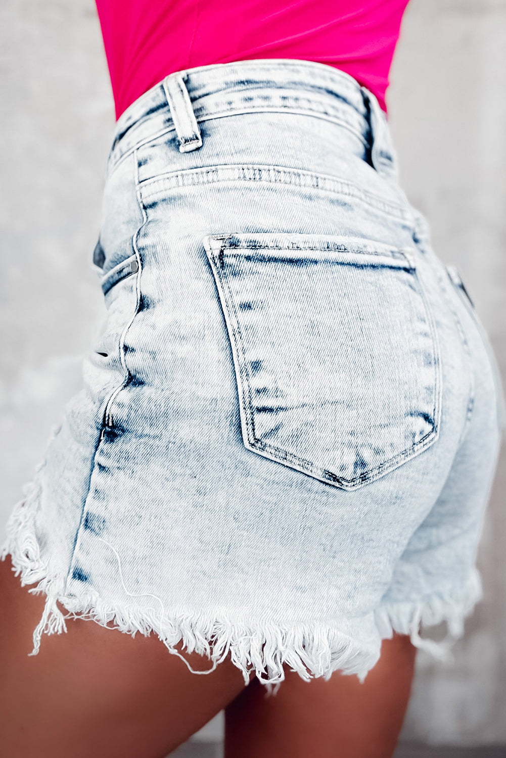 Light blue acid wash crossed raw edge denim shorts from Mommas Hive, casual bottoms with distressed finish and raw hem.