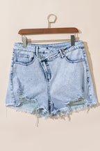 Light blue acid wash denim shorts with crossed raw edges from Mommas Hive, made of cotton, polyester, and elastane.