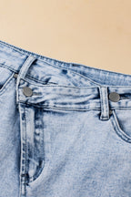 Light blue acid wash denim shorts by Mommas Hive with crossed raw edge design and raw hem, made from cotton, polyester, and elastane.