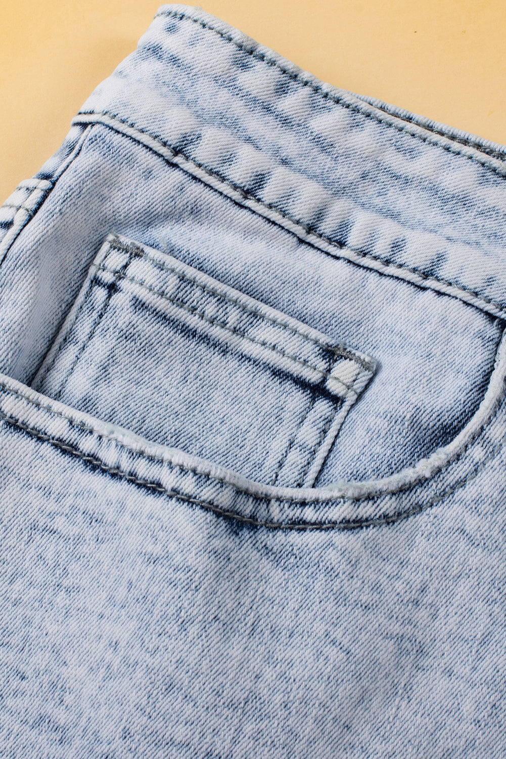 Light blue acid wash crossed raw edge denim shorts from Mommas Hive, featuring distressed hem and casual fit.