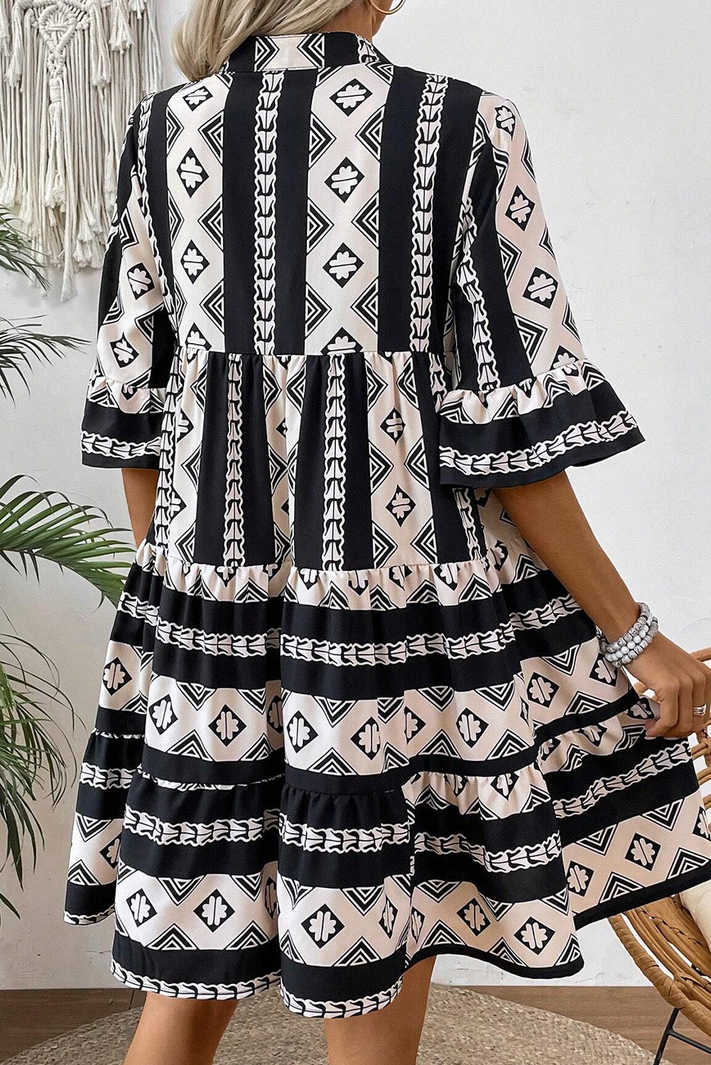 Black geometric print V-neck ruffled mini dress by Mommas Hive, featuring a stylish design and lightweight polyester fabric.