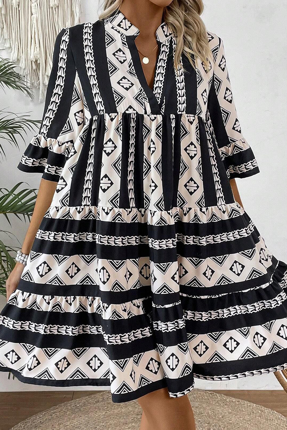 Black geometric print V-neck ruffled mini dress by Mommas Hive, featuring a stylish and feminine design with ruffled details.