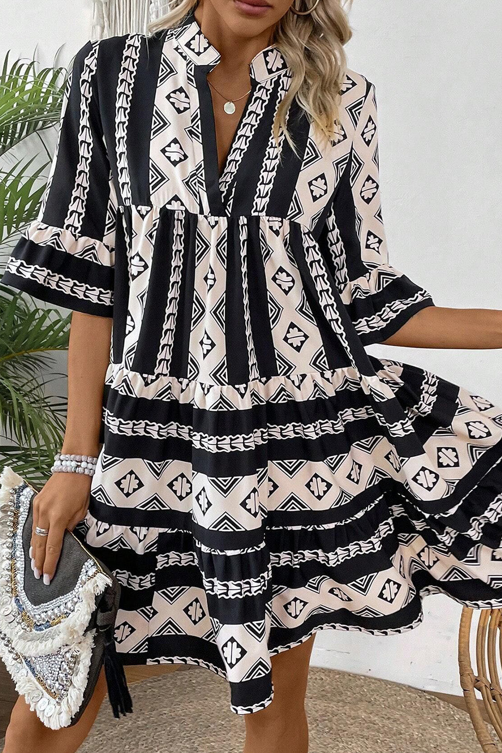 Black geometric print V-neck ruffled mini dress by Mommas Hive, showcasing stylish ruffle details and a fitted silhouette.
