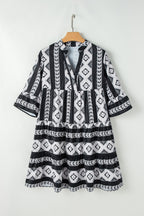 Black geometric print V-neck ruffled mini dress by Mommas Hive, featuring a stylish design and lightweight polyester fabric.