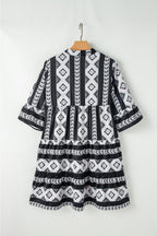 Black geometric print v-neck ruffled mini dress by Mommas Hive, featuring a stylish design and ruffle details.