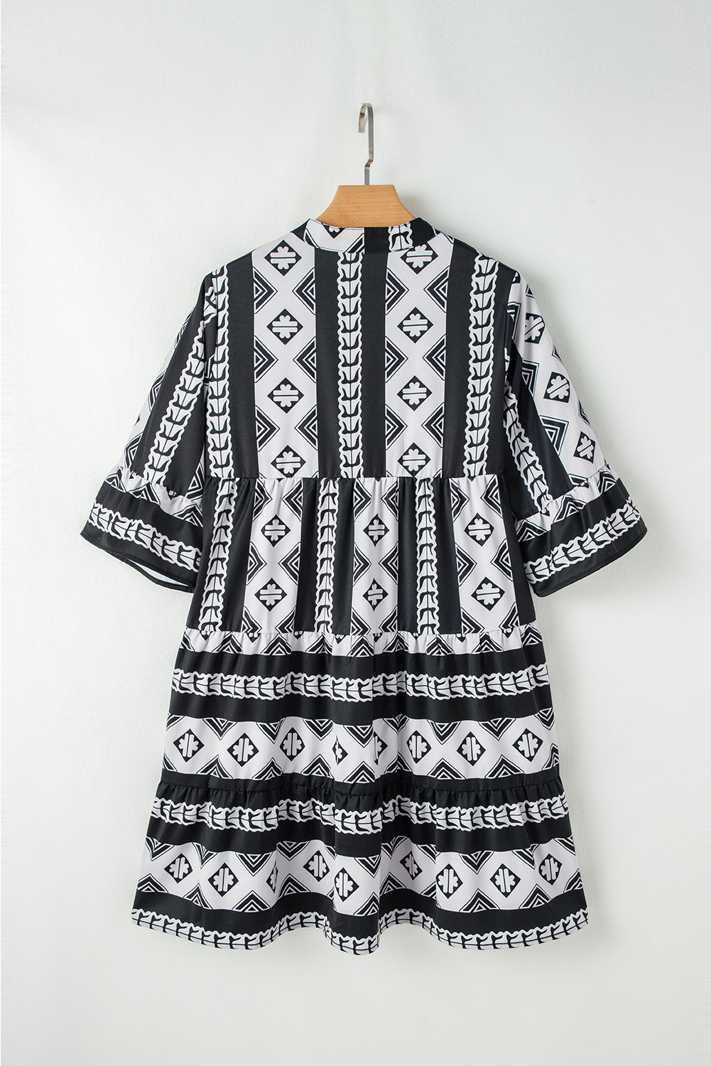 Black geometric print v-neck ruffled mini dress by Mommas Hive, featuring a stylish design and ruffle details.