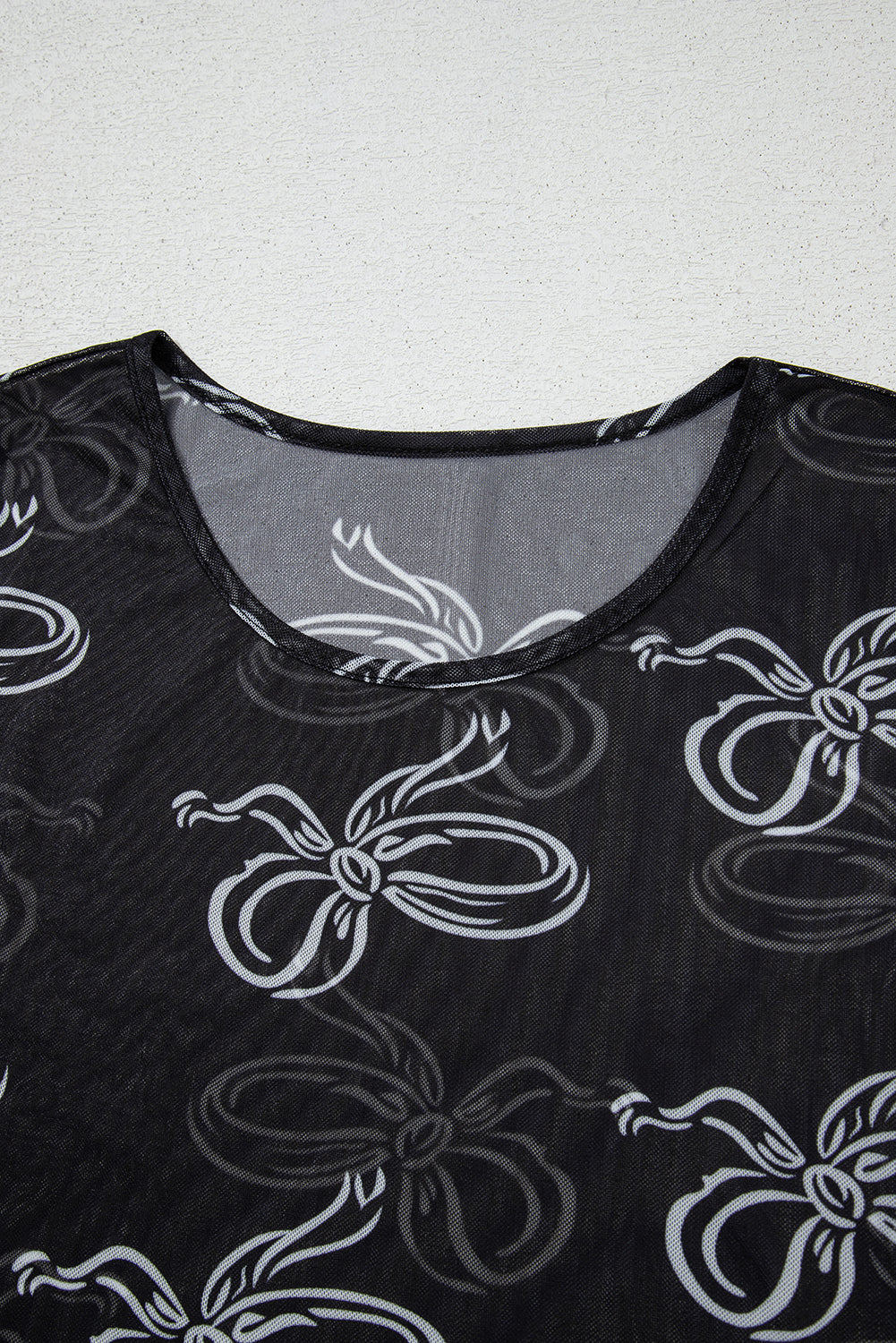 Black round neck mesh top with bow print from Mommas Hive, long sleeve design, made of polyester and elastane.