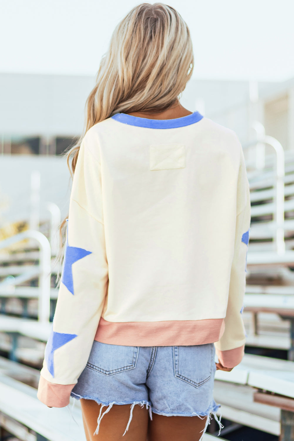 Light pink oversized sweatshirt with star patchwork and exposed seams by Mommas Hive, made of polyester and cotton blend.