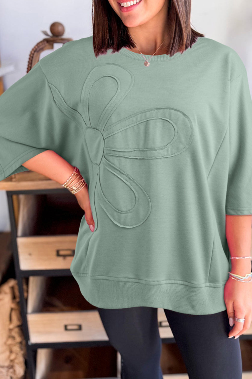 Mommas Hive floral patched half sleeve tunic top in aqua, made of polyester, cotton, and elastane, displayed on a hanger.