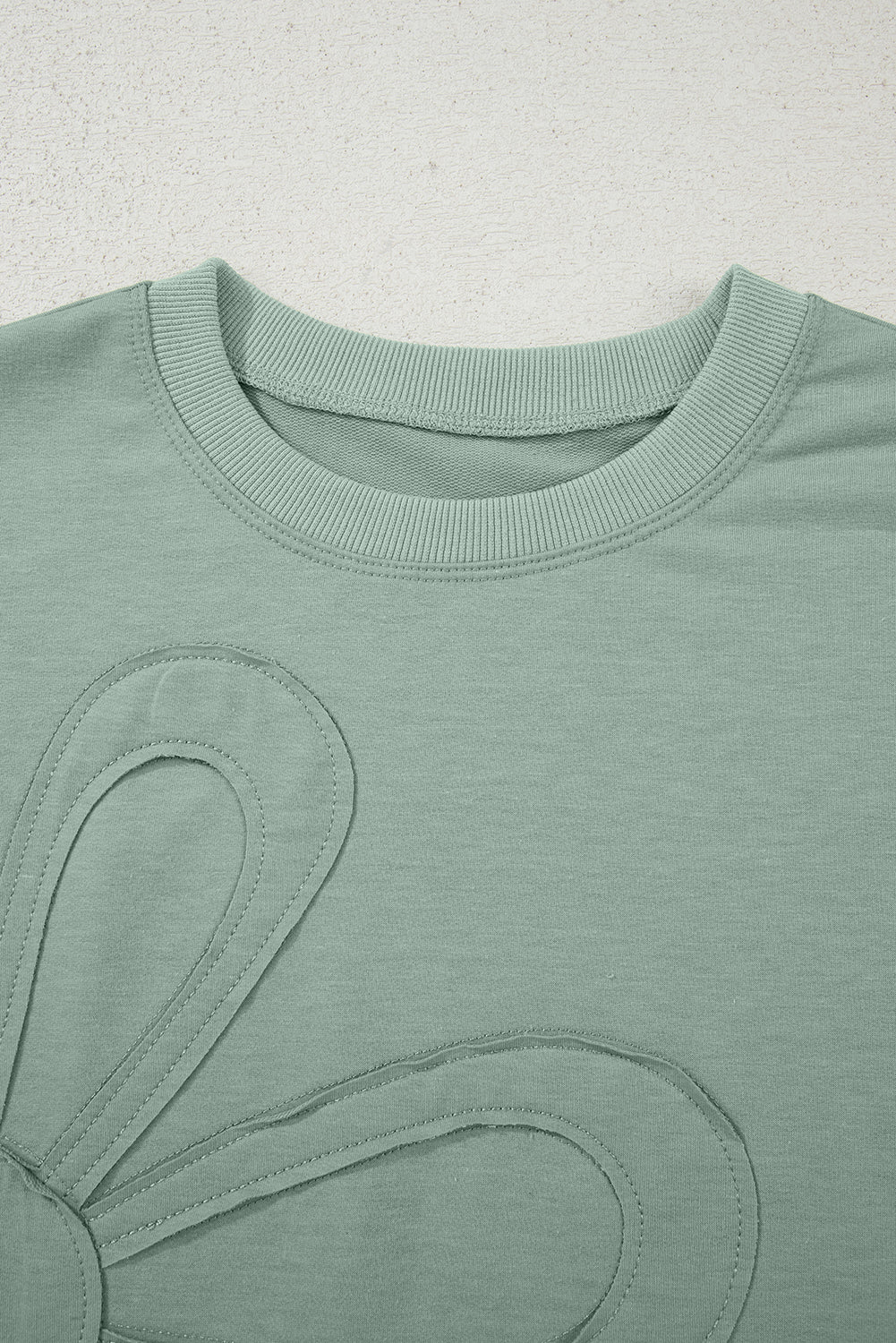 Mommas Hive floral patched half sleeve tunic top in aqua, made of polyester, cotton, and elastane, displayed on a hanger.