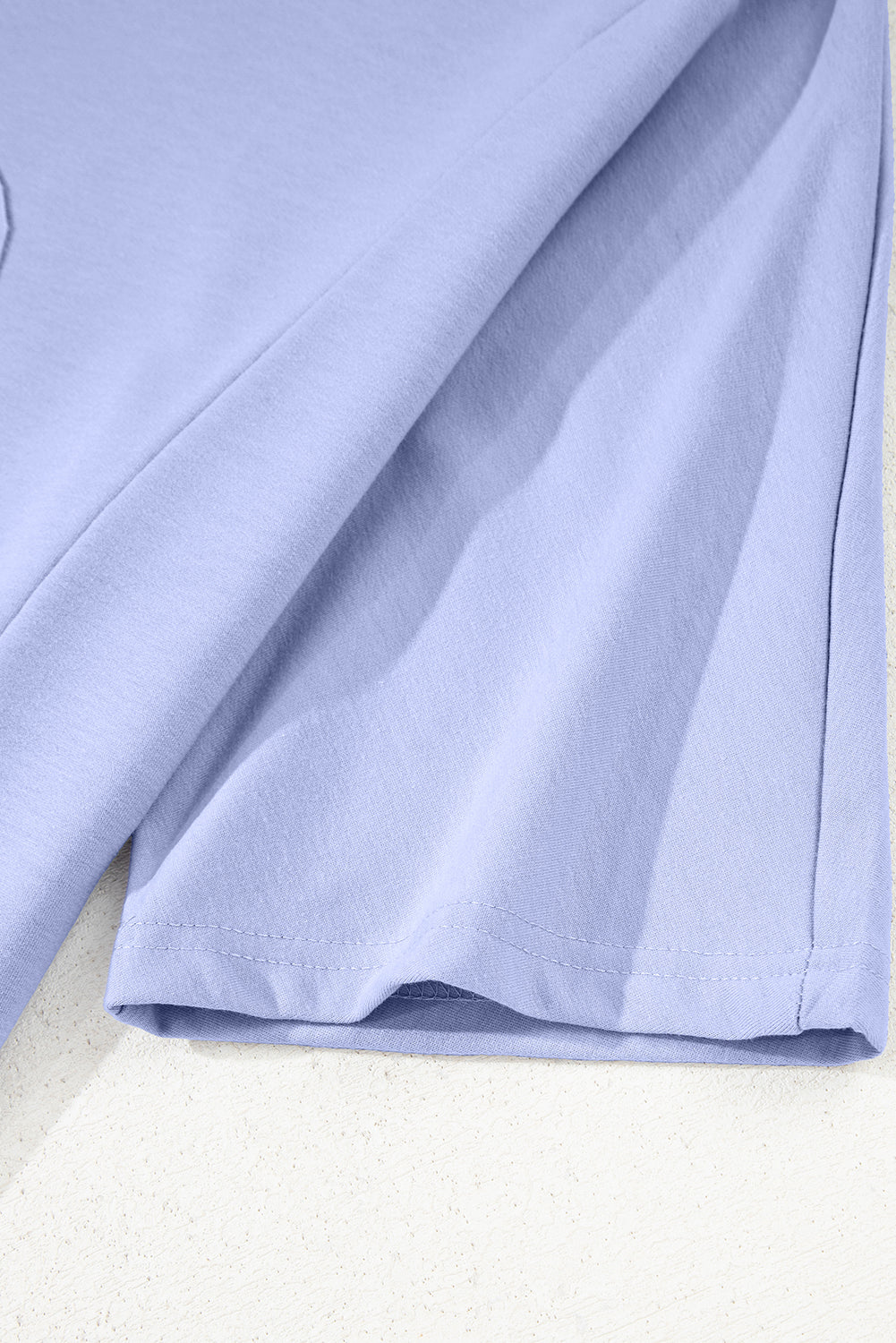 A floral patched half sleeve tunic top by Mommas Hive in aqua with polyester, cotton, and elastane fabric, displayed on a hanger.