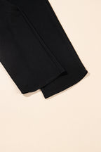 Black textured ruffled sleeve zipped top with wide-leg pants set by Mommas Hive, featuring polyester-elastane fabric and stylish design.