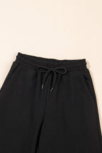Black textured ruffled sleeve zip-up top with wide-leg pants set by Mommas Hive, featuring polyester-elastane fabric and stylish design.