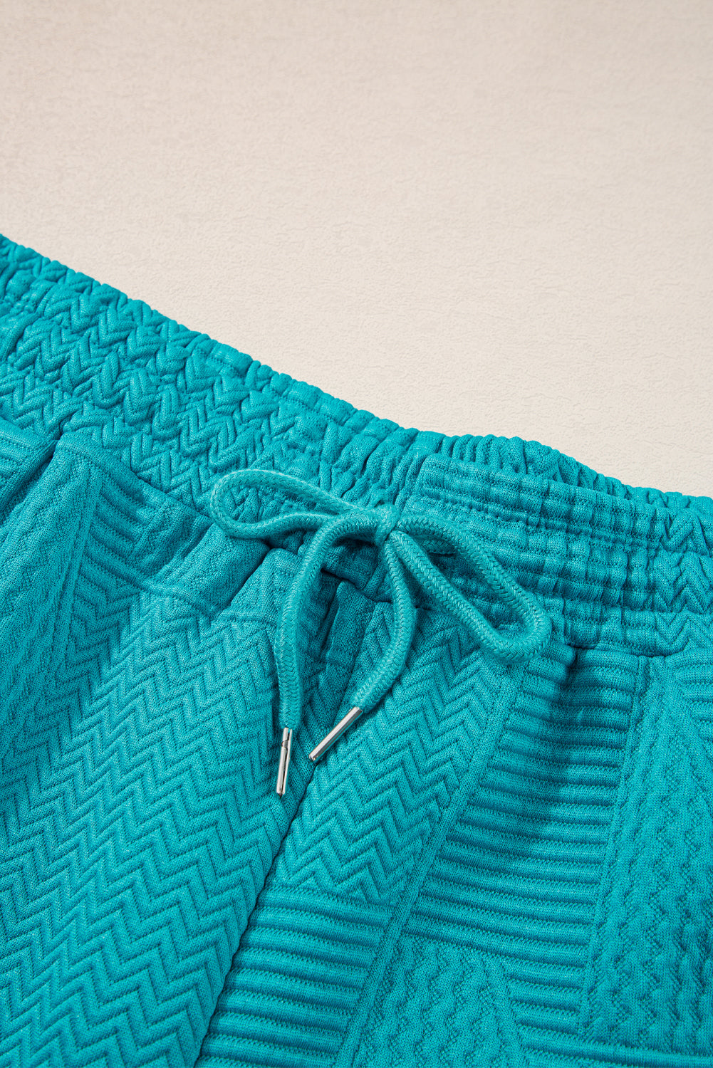Mommas Hive textured ruffle split top and drawstring shorts two-piece set, polyester and elastane, stylish and comfortable for casual wear.