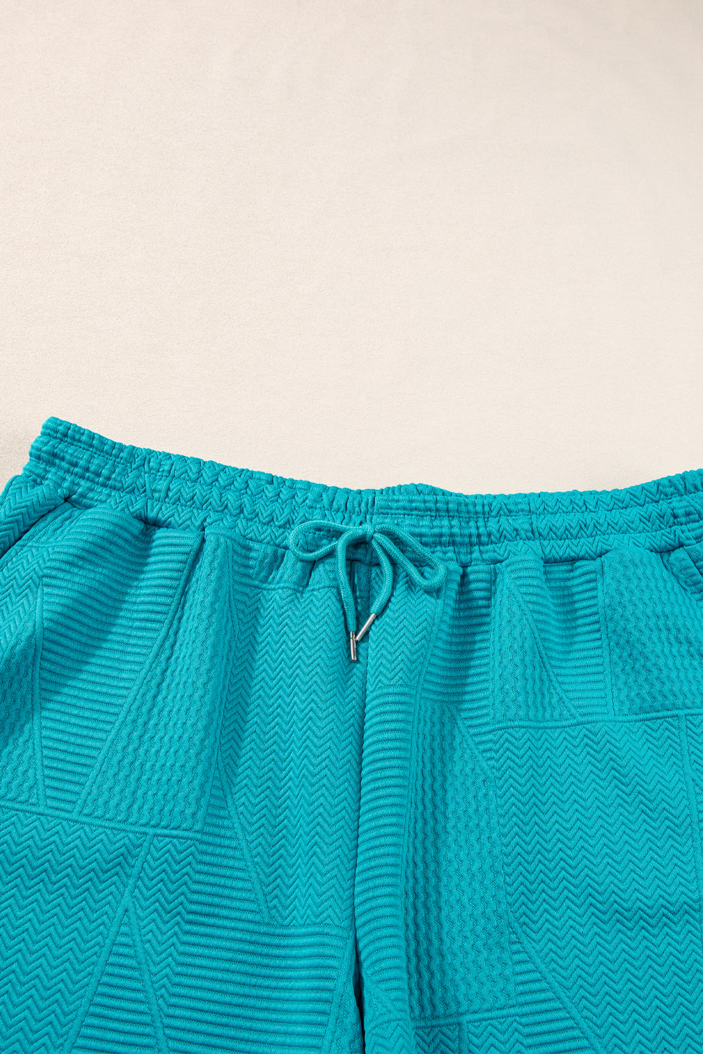 Mommas Hive textured ruffle split top and drawstring shorts two-piece set, featuring polyester-elastane fabric and stylish design.