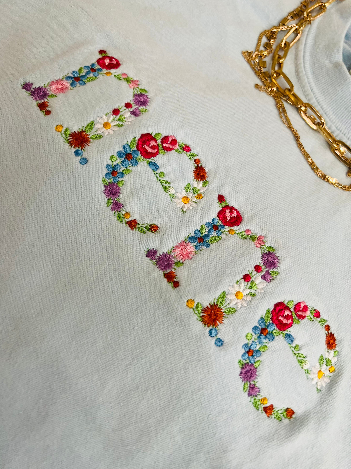 Blue Nene Floral Embroidered T-shirt by P&PD Wholesale, featuring colorful floral embroidery on the front.